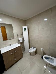 a bathroom with a sink and a toilet and a mirror at Vila do Ilhéu in Vila Franca do Campo