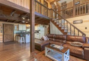 a living room with a leather couch and a staircase at Rustic Cabin Retreat - Hot tub - Fire pit - BBQ - in Island Park
