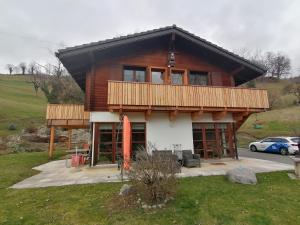 a large wooden house with a deck on top at Les Comblés des Combes in Ollon