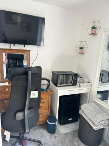 a room with a desk with a chair and a television at Cosy living space in Orgreave