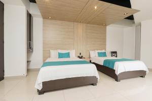 two beds in a room with white and blue at Hotel El Alba in Cali +38 photos