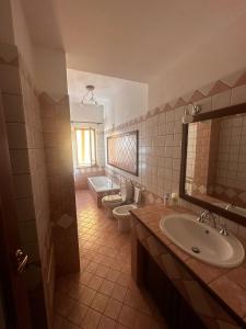 un bagno con due WC, un lavandino e una vasca di Appartamento Franca a Capo dʼOrlando