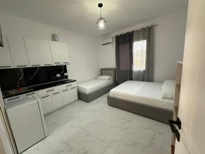 a bedroom with two beds and a tv and a kitchen at Villa Aliaj in Vlorë