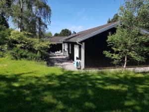 a black and white building with a grass yard at Bright Summer House Near Hyllingebjerg Beach in Melby
