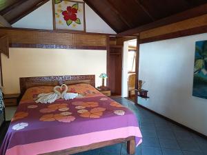 a bedroom with a bed with a purple comforter at La PERLE de MOOREA Fare MOANA ITI Bord de lagon in Orufara