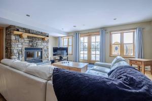 a living room with a couch and a fireplace at Forest Getaway, Soak in the Spa, Sauna, Fireplace in Mille-Isles