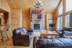 a living room with couches and a fireplace at Forest Getaway, Soak in the Spa, Sauna, Fireplace in Mille-Isles