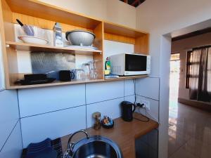 a kitchen with a sink and a microwave at Duineveld Self Catering Cottage in Kalkrand
