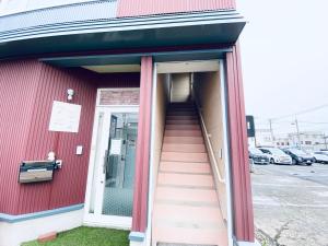 a stairway leading into a red building with a door at 優ハウス夢ハウス2階 in Furano