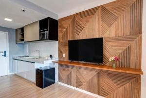 cocina con pared de madera y TV de pantalla plana en Campos do Jordão - Gran Paradiso Resort, en Campos do Jordão