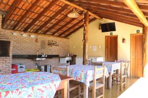 a dining room with tables and chairs and a kitchen at Pousada Alto do Bau in Conceição do Mato Dentro
