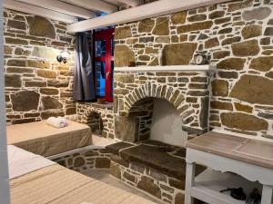 a stone room with two beds and a stone fireplace at Rodakas Rooms-Aimilia in LivadhokhÃ³rion