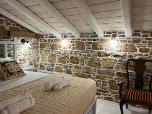 a bed in a room with a stone wall at Rodakas Rooms-Aimilia in LivadhokhÃ³rion