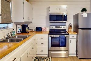 Una cocina con gabinetes blancos y un refrigerador de acero inoxidable. en Coastal Holly Retreat, en Holly Hill