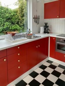 a kitchen with red cabinets and a black and white checkered floor at Cozy Red Cottage By Kalø Vig With Seaview in Hornslet