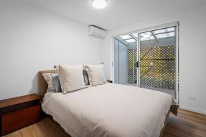 Un dormitorio con una cama blanca y una ventana. en 10-60 Peregian Esplanade Peregian Beach, en Peregian Beach