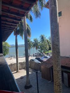 a view of a beach with palm trees and cars at Suíte no centro in Saquarema