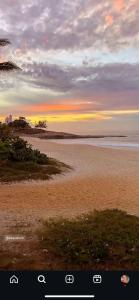 a view of a beach with a sunset in the background at Suíte no centro in Saquarema