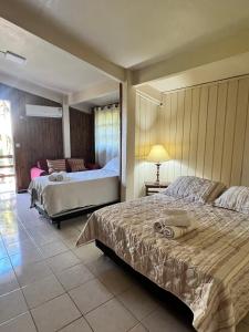 ein Hotelzimmer mit zwei Betten und einem Wohnzimmer in der Unterkunft Refúgio Beija Flor SC in Praia Grande