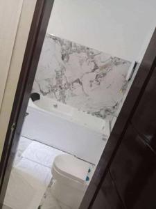 a bathroom with a white toilet and a marble wall at Tilano Whitestone Resort in Maria