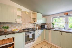 a kitchen with white cabinets and a stove top oven at Traditional Highland Cottage Near Loch Ness in Drumnadrochit