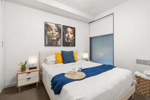 une chambre avec un grand lit blanc avec des oreillers bleus et jaunes dans l'établissement The South Yarra Jewel, à Melbourne