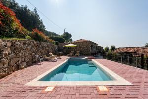 einen Pool mit einer Terrasse und einer Steinmauer in der Unterkunft Maria Felícia Village in Castelo de Paiva
