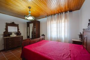 Schlafzimmer mit einem roten Bett, einer Kommode und einem Spiegel in der Unterkunft Maria Felícia Village in Castelo de Paiva