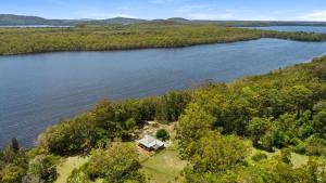 une vue aérienne d'une maison au milieu d'un lac dans l'établissement Cutlers Cottage, à Bombah Point 1 autre photo