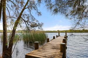un quai en bois au milieu d'un lac dans l'établissement Cutlers Cottage, à Bombah Point