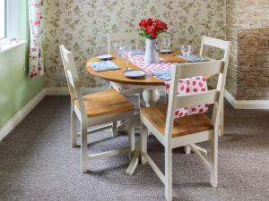ein Holztisch mit Stühlen und einer Vase mit Blumen darauf in der Unterkunft The Miners Cottage in Loftus
