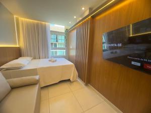 a hotel room with a bed and a flat screen tv at EcoMirage - Flats Premium - Porto de Galinhas in Porto De Galinhas