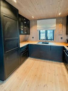 een keuken met zwarte kasten en een houten vloer bij Modern Cabin By Skeikampen's Ski Trails in Svingvoll