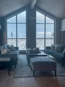a living room with couches and tables and large windows at Modern Cabin By Skeikampen's Ski Trails in Svingvoll