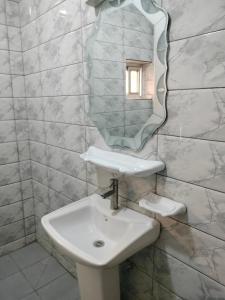 ein Badezimmer mit Waschbecken und Spiegel an der Wand in der Unterkunft Résidence Diakhaby in Conakry