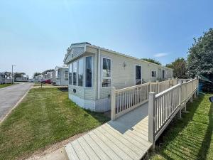 a mobile home with a porch and a wooden deck at Lovely Wheelchair Friendly Caravan At Skipsea Sands In Yorkshire Ref 41167Wf in Barmston