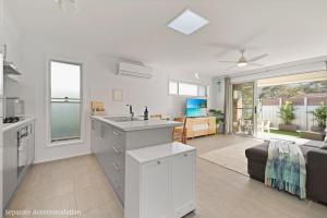 an open kitchen and living room with a couch at Beachstay Hideaway Vincentia by Book Jervis Bay in Vincentia