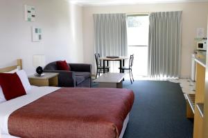a hotel room with a bed, desk, chair and a television at Rose Garden Motel in Geelong