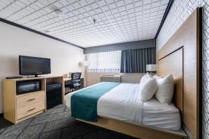 a hotel room with a bed and a flat screen tv at Sternwheeler Hotel & Conference Centre, Trademark by Wyndham in Whitehorse