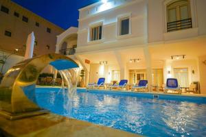 a swimming pool with a fountain in front of a house at Malek Hotel in Sheikh Zayed