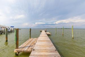a wooden dock in the water with a boat at Wolf Bay Villas in Orange Beach
