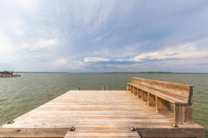 a wooden pier on a lake with a cloudy sky at Wolf Bay Villas in Orange Beach +24 photos