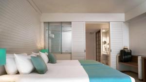 a bedroom with a large bed with blue and white pillows at ANA InterContinental Manza Beach Resort by IHG in Onna