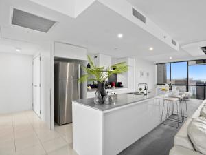 cocina blanca con nevera de acero inoxidable en 2BR Unit Heart of Surfers Paradise - Spa, Pool, en Gold Coast
