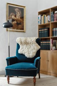 a blue chair in a living room with a book shelf at Unique Stay At Odden Manor & Museum in Hjørring