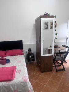 a bedroom with a bed and a mirror and a table at Kitnet aconchegante in Pedra de Guaratiba