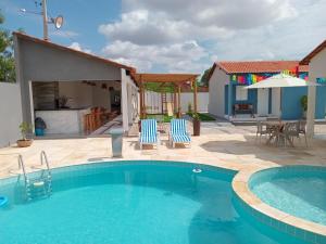 a swimming pool with two chairs and a house at Villa Chalés in Piranhas