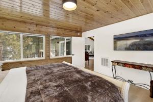 ein Schlafzimmer mit großem Bett und Holzdecken in der Unterkunft Sueños Azules- Fawnskin Retreat Cottage in Big Bear in Fawnskin