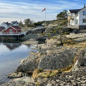 a flag on a hill next to a body of water at Modern Beach House On Car-Free Vestre Sandøya in Kilen +32 photos