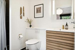 a white bathroom with a toilet and a sink at Modern Sleek House In Gedser in Gedser +28 photos